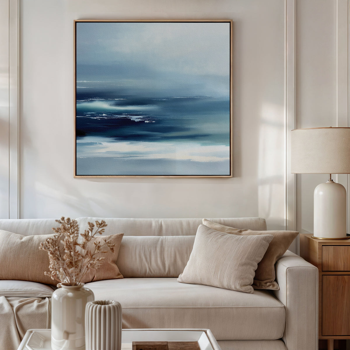 A modern living room with a light beige sofa, neutral cushions, and dried florals. The Sapphire Current Canvas Art - Square hangs above the sofa, bringing a calming touch to this Nordic Park-inspired space.