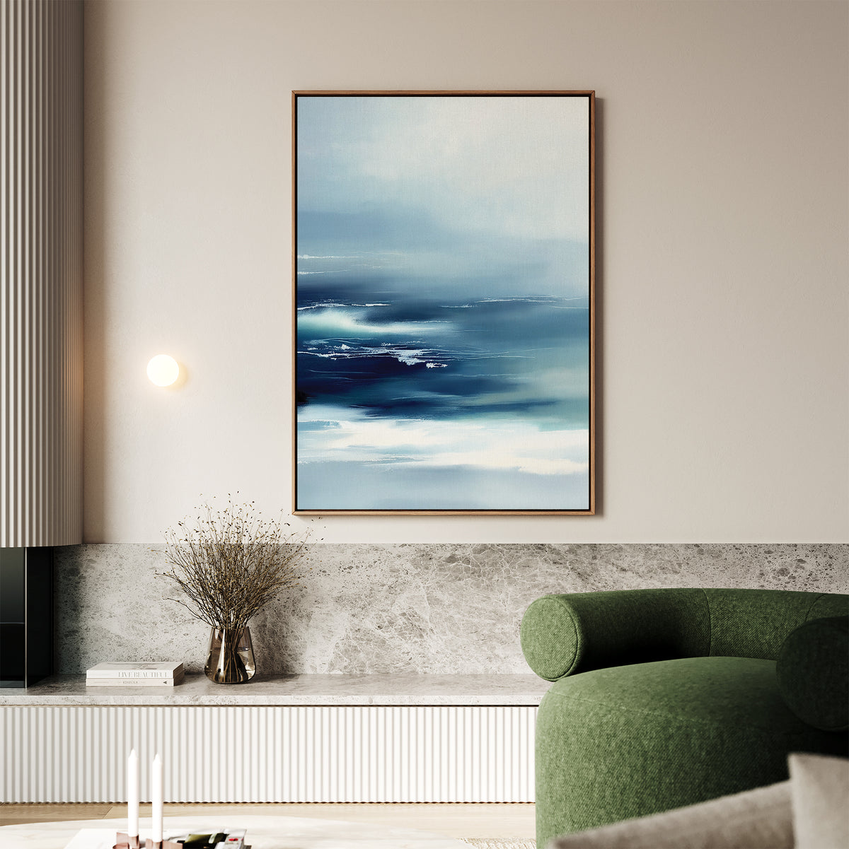 A modern living room with a green curved sofa, Sapphire Current Canvas Art - Vertical as serene wall art, a small wall light, a vase with dried branches, and minimalist decor on a marble-topped console.