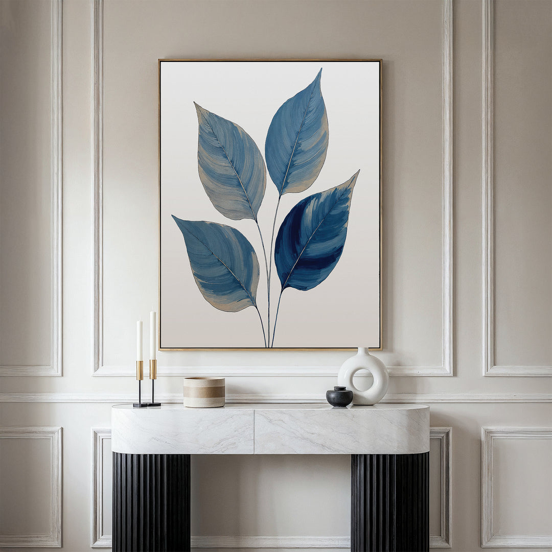A modern room features calming blue wall art—a Sapphire Leaves Canvas Art - Vertical displayed above a white marble console table, which holds decorative objects like candles, a round sculpture, and a lidded container.