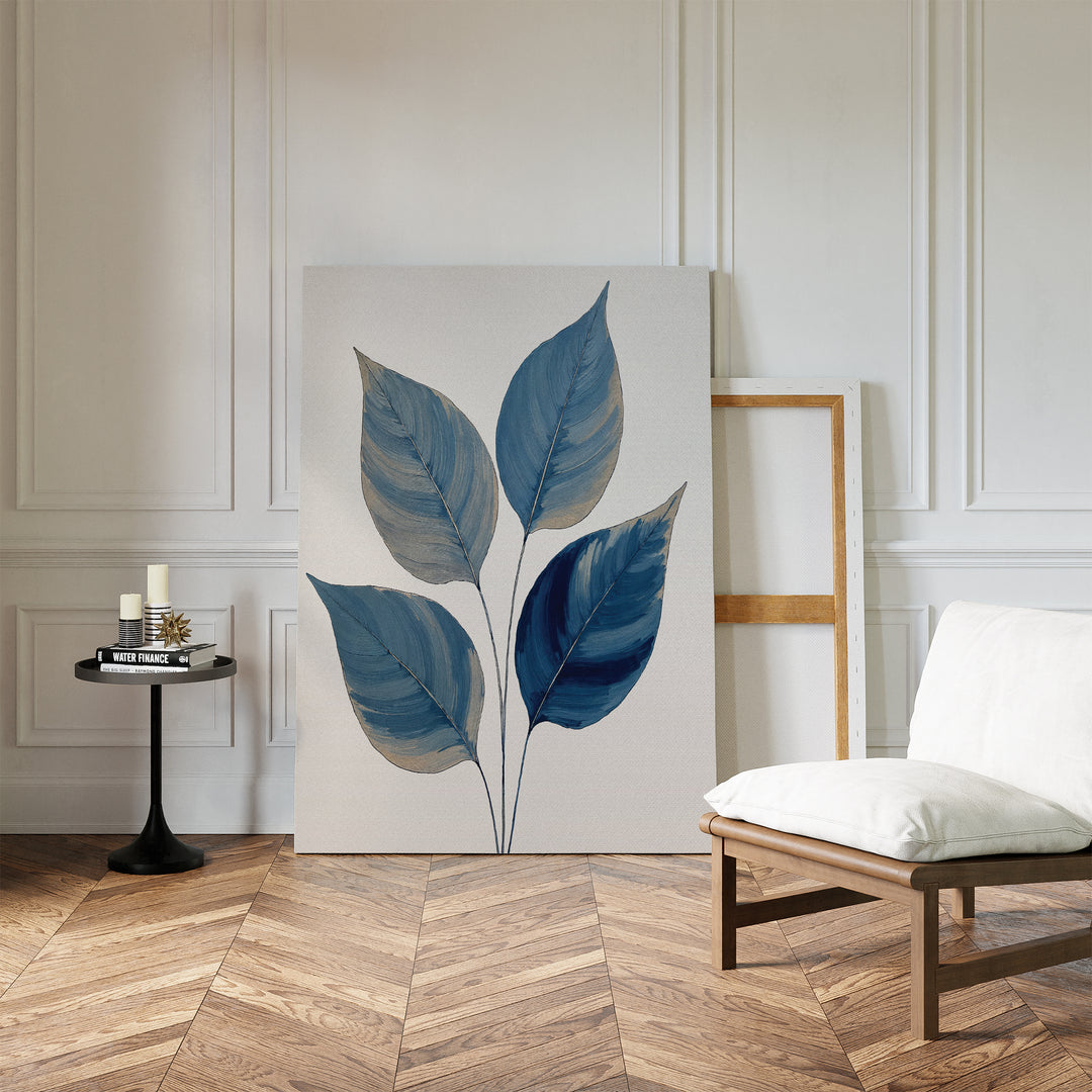 A modern room with white paneled walls, herringbone wood floor, a cushioned chair, round black side table with candles and books, and the calming Sapphire Leaves Canvas Art - Vertical botanical print resting against the wall.