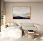 A modern living room with a light beige sectional, low wooden coffee table, black bowl, and tall plant is filled with natural light. The Sapphire Tides Canvas Art - Horizontal adds a contemporary touch as striking wall decor.