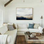 A bright, cozy living room with white shiplap walls, a large white sectional sofa, assorted pillows, a rustic wooden coffee table, and modern wall decor—a Sapphire Tides Canvas Art - Horizontal—displayed above the sofa.