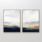 The Sapphire Tides - Set Of 2 features framed abstract prints with soft blends of cobalt blue, beige, and white, evoking a serene, cloudy landscape—ideal for adding a modern touch to your living room.