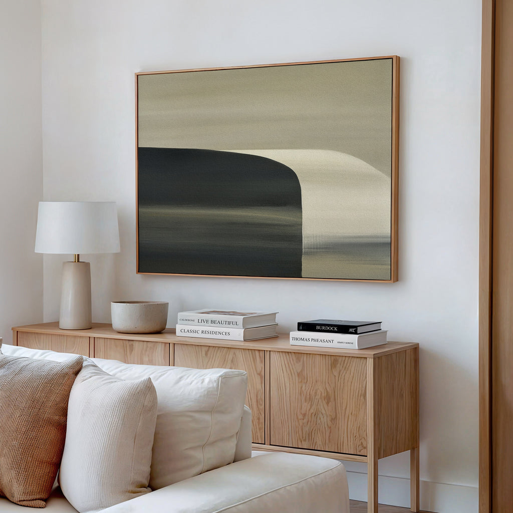 A modern living room with minimalist decor features a light wood sideboard, books, a lamp, decorative objects, and the Sculptural Forms Canvas Art - Horizontal in earthy tones hanging above a beige sofa on a white wall.