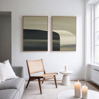 Minimalist living room with a gray sofa, light wooden chair, small white table, and lit candles. Two abstract paintings hang above. Sculptural Forms - Set Of 2 add artistry near large windows that flood the modern space with natural light.