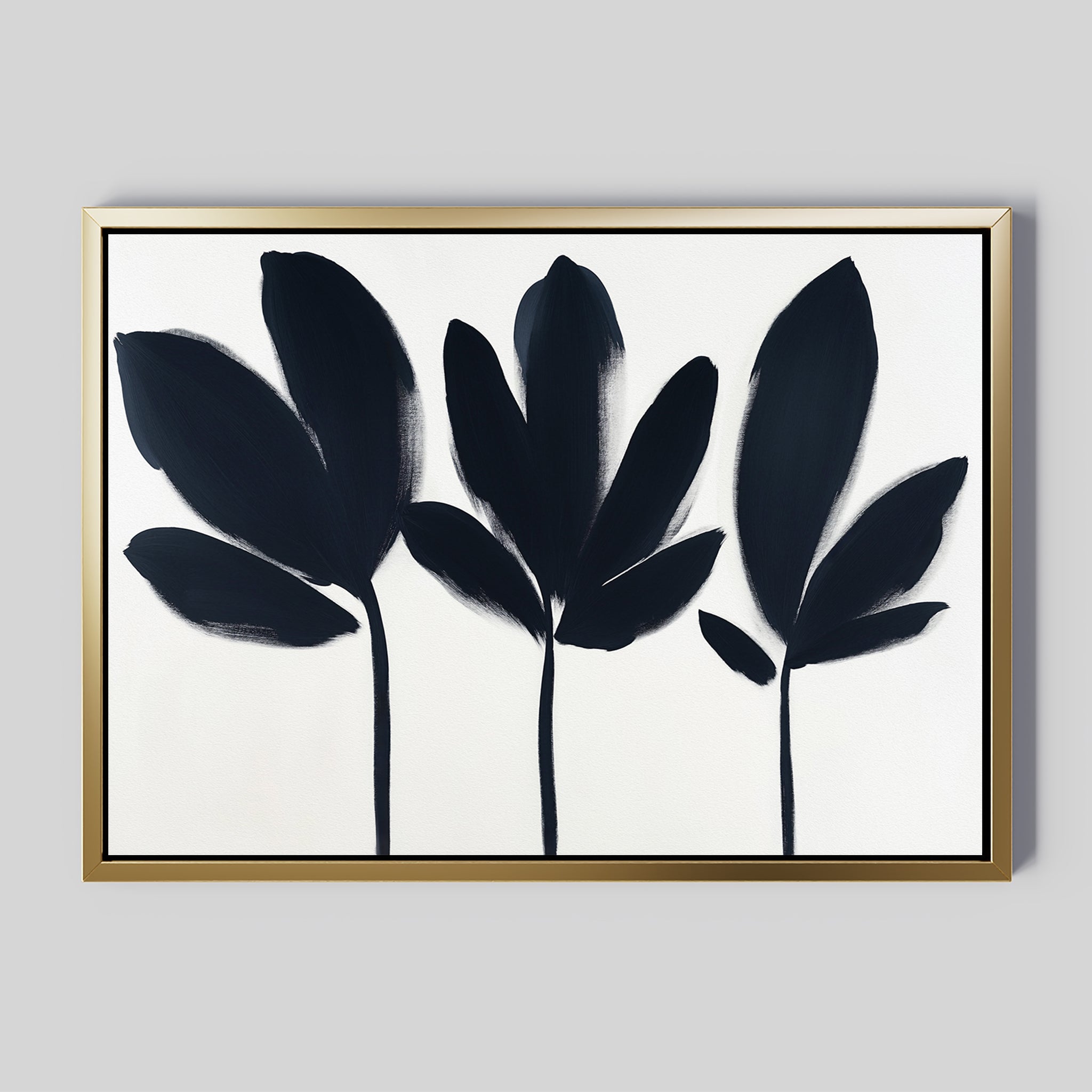 The Shadow Stems Canvas Art - Horizontal features three abstract black botanical silhouettes with stems on white, framed in gold. Its bold leaves and minimalist style make it a perfect elegant accent for modern living rooms.