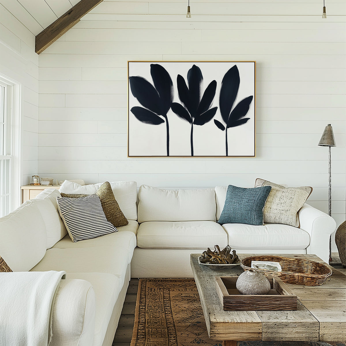 A cozy living room with a white sectional, assorted pillows, a wood coffee table with décor, and the Shadow Stems Canvas Art - Horizontal on a white shiplap wall—an ideal modern accent.