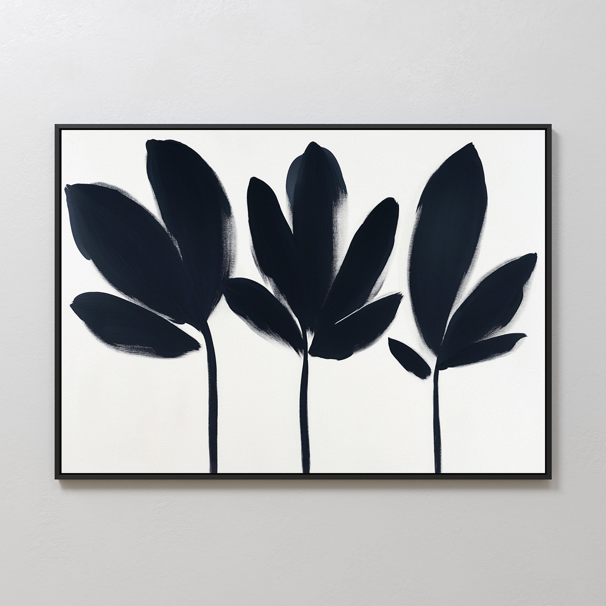 Shadow Stems Canvas Art - Horizontal: A minimalist canvas with three abstract botanical silhouettes in broad leaves on a white background, framed in thin black, ideal for adding modern elegance to your living room wall.