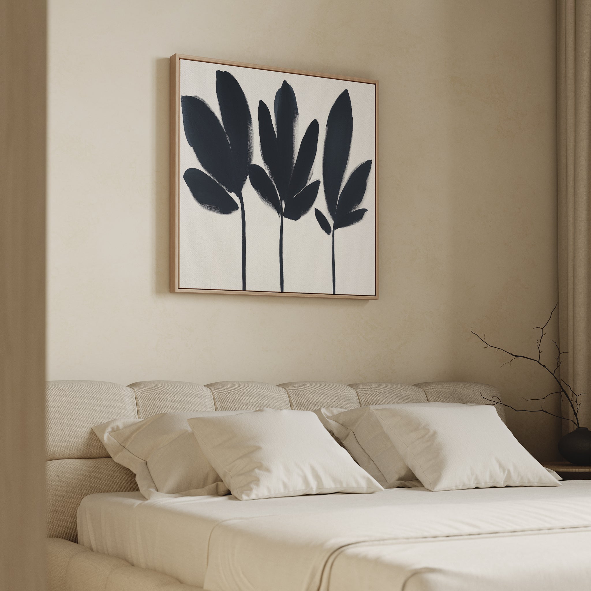 Minimalist bedroom with a beige upholstered bed, white bedding, and four pillows. Above the bed hangs the Shadow Stems Canvas Art - Square in a wooden frame. A bare branch in a vase and beige curtains accent the right side of the room.