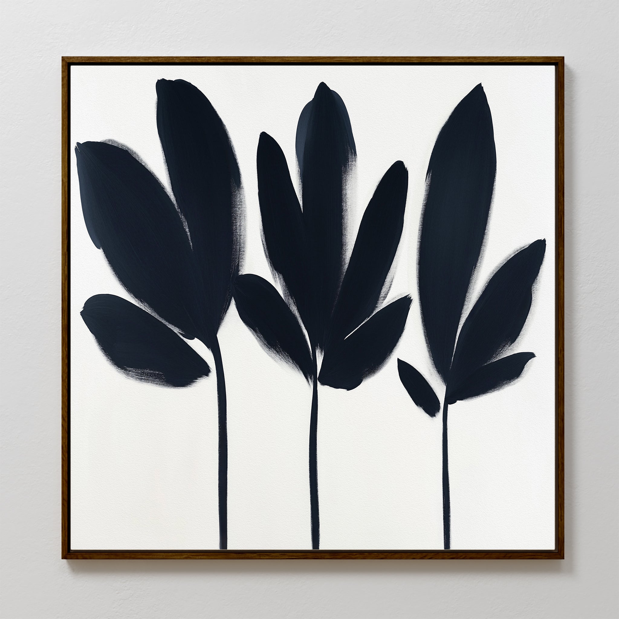 The Shadow Stems Canvas Art - Square features three abstract black botanical silhouettes with thick stems on white, framed in slim dark wood. Bold, textured brushstrokes make it a perfect minimalist accent for modern living spaces.