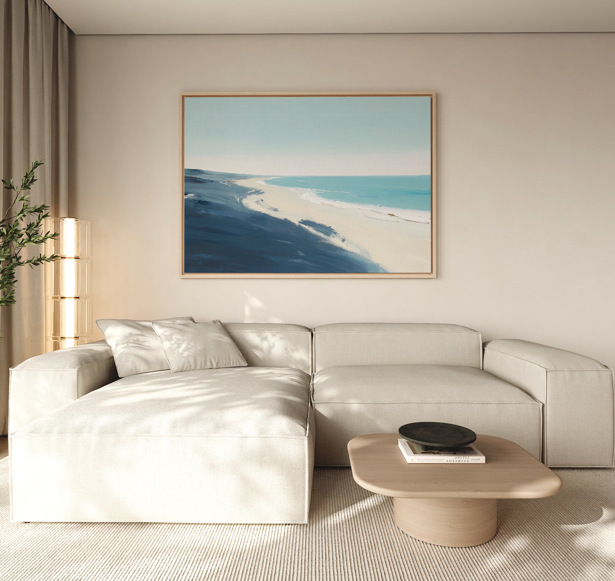 A modern living room features a light beige sectional sofa, a low wooden coffee table, and the Shifting Tides Canvas Art - Horizontal depicting a coastal landscape above the sofa. Natural light brightens the minimalist space.