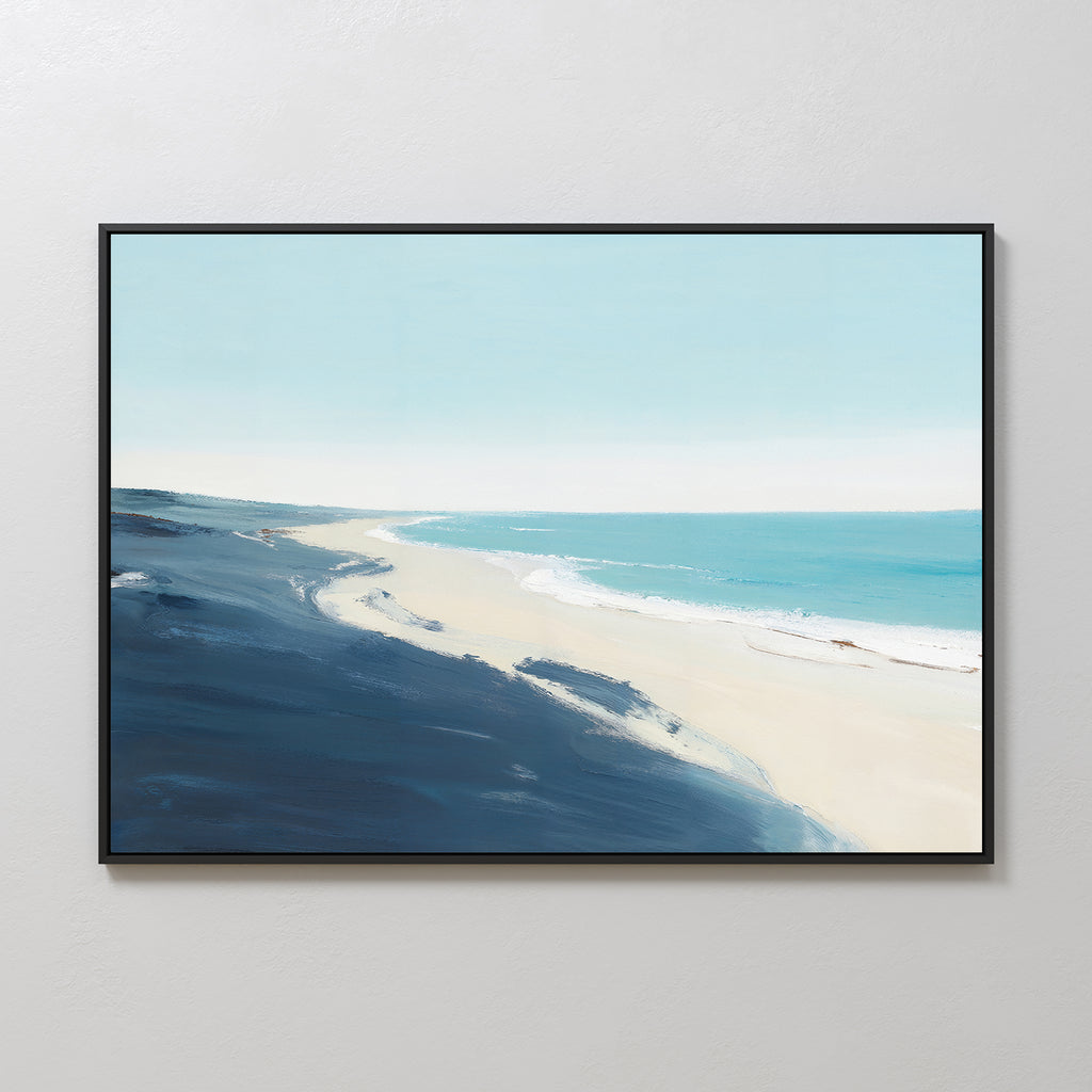 The Shifting Tides Canvas Art - Horizontal, showing a serene beach with deep blue water and a pale sky, is framed and displayed on a plain, light-colored wall.