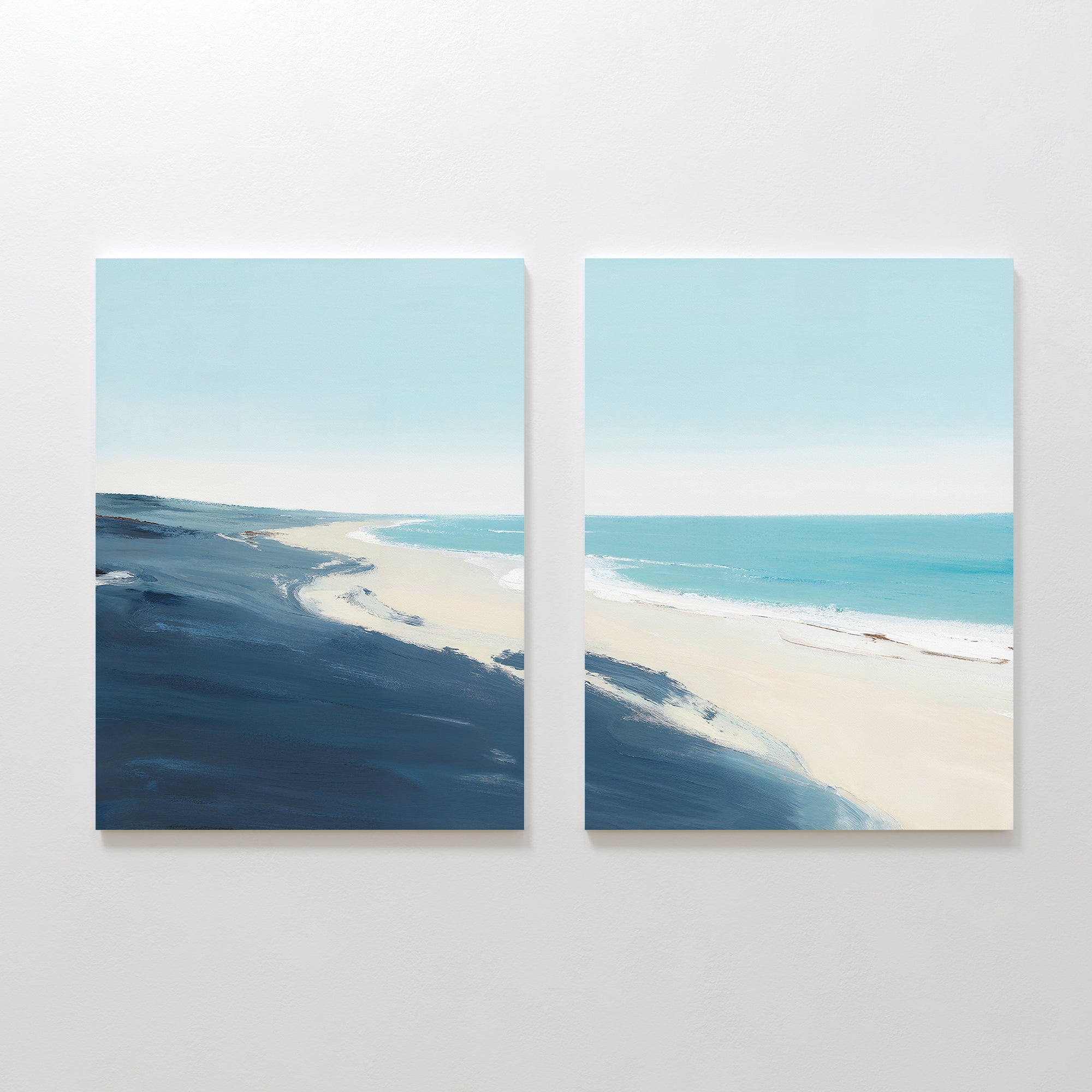 Shifting Tides - Set of 2 features minimalist seaside wall art with soft blue skies, deep blue ocean, and a sandy shore—brought to life with broad brushstrokes and airy colors.