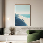 A modern living room with a green curved sofa, Shifting Tides Canvas Art - Vertical above, a round wall light, and a vase of dried flowers on a marble ledge. The space features neutral tones and minimalist Nordic Park-inspired decor.