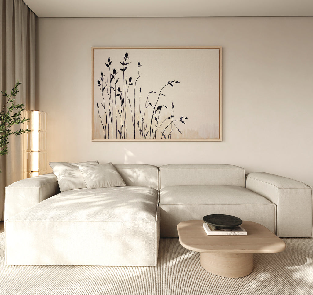 Minimalist living room featuring a light beige sectional, Nordic decor, wooden coffee table with dark bowl, soft natural light, and neutral tones. The serene space is completed by Silhouette Meadow Canvas Art - Horizontal and a leafy plant.