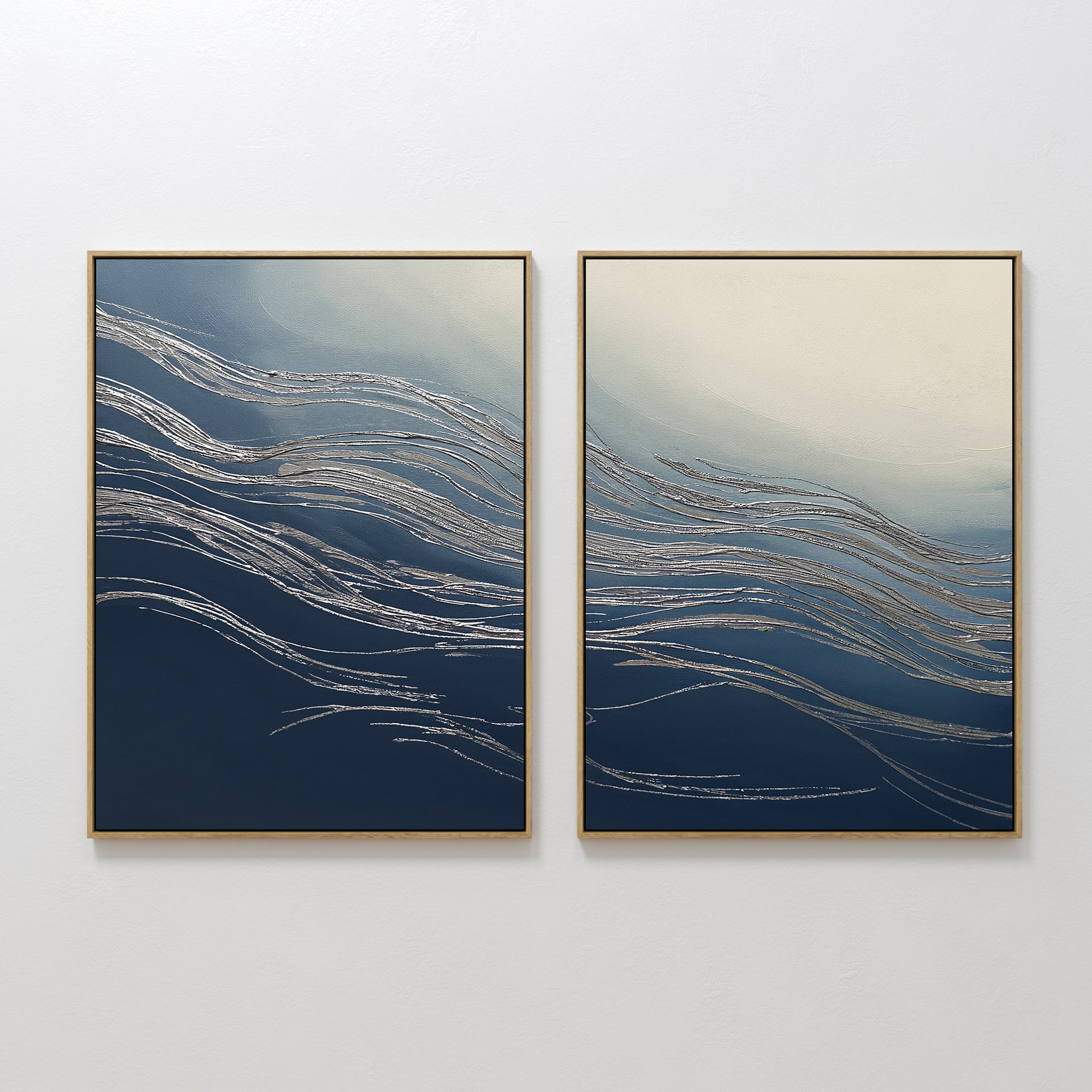 The Silver Current - Set Of 2 features two framed abstract prints with blue and cream backgrounds, accented by flowing silver lines, displayed side by side to bring a touch of contemporary sophistication to any room.