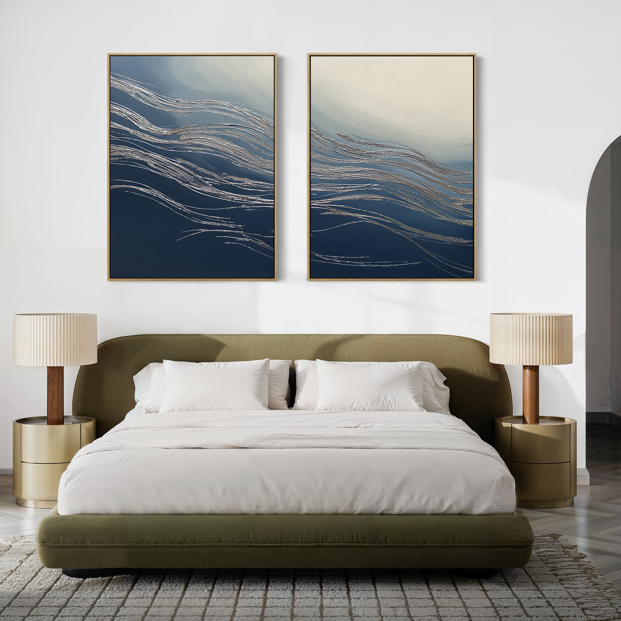 A modern bedroom featuring an olive green upholstered bed with white bedding, two beige nightstands and lamps, and contemporary flair brought by 'Silver Current - Set Of 2' abstract art in blue and gold above the headboard.