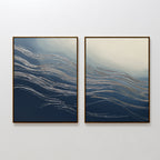 The Silver Current - Set Of 2 features framed abstract prints with flowing silver lines on deep blue and beige backgrounds—ideal wall art for adding contemporary sophistication to a minimalist white wall.