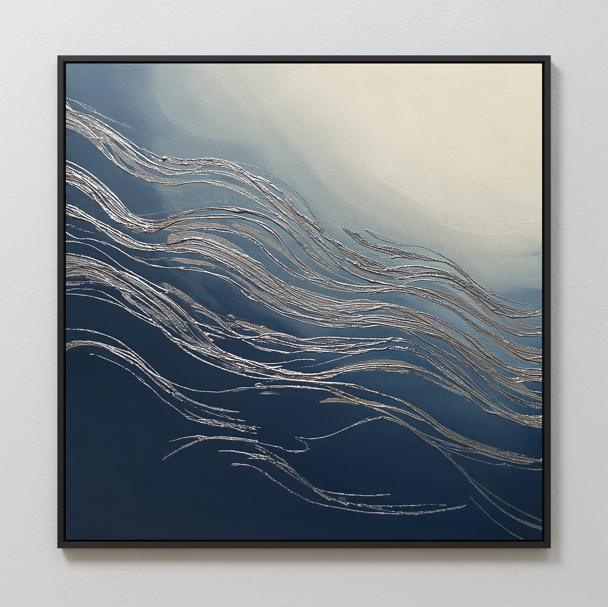 The Silver Current Canvas Art - Square features flowing silver lines over a dark blue to light cream gradient, reminiscent of waves or wind. Framed in black, this contemporary wall art brings sophisticated style to any space.