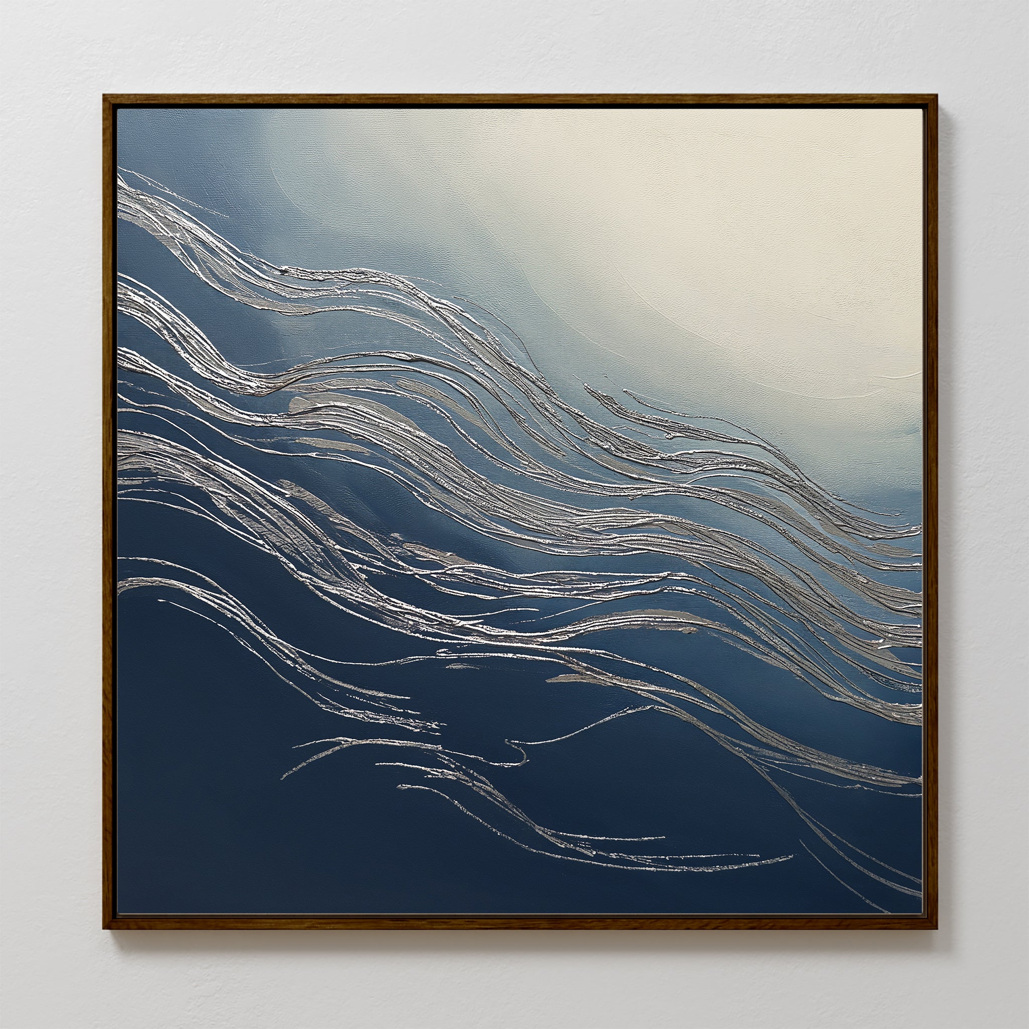 The Silver Current Canvas Art - Square features silver wavy lines over a blue and white gradient, evoking water or wind movement. Framed in thin dark wood, it brings contemporary sophistication to any light-colored wall.