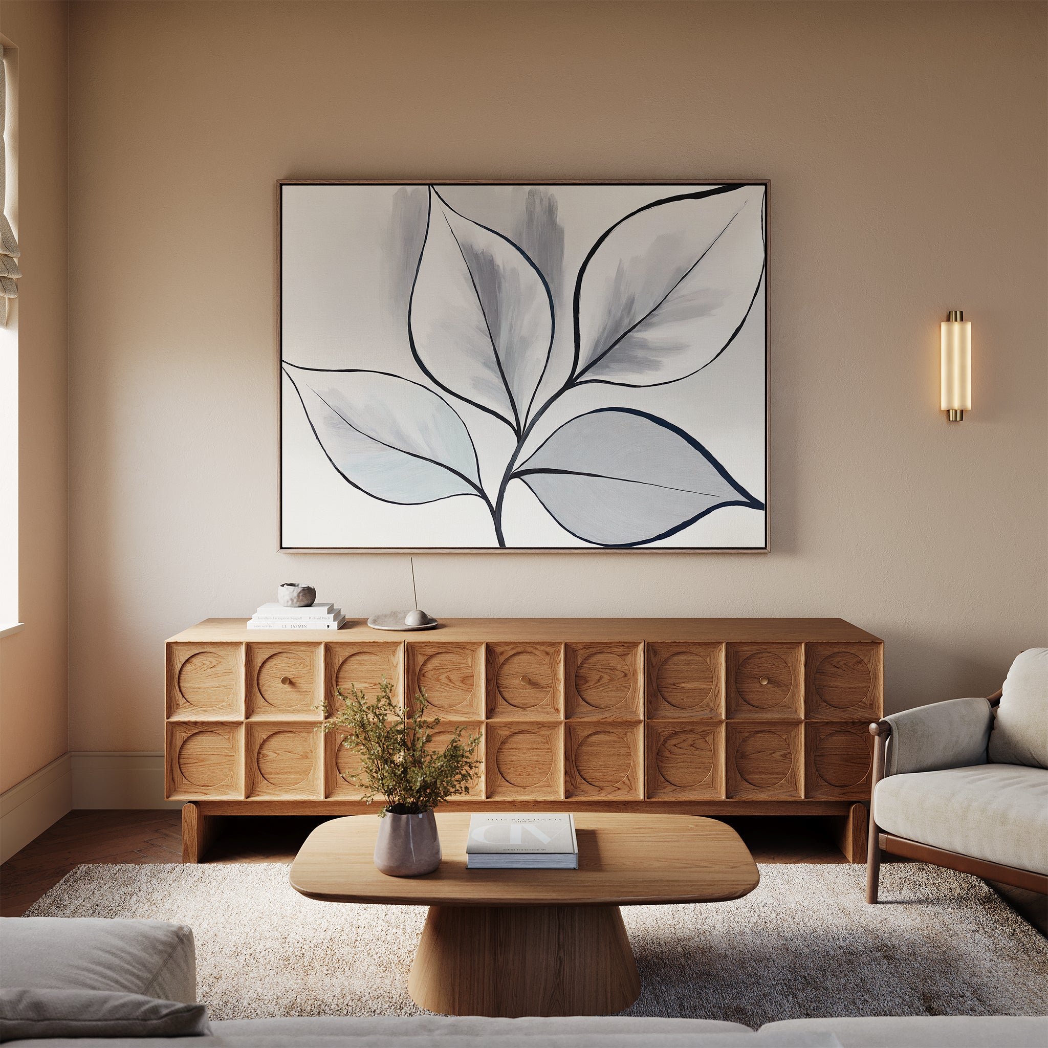 A modern living room features a light wood coffee table, textured wooden sideboard, beige sofa, neutral rug, wall sconce, and minimalist Silver Leaves Canvas Art - Horizontal. A small plant on the coffee table adds to the contemporary decor charm.