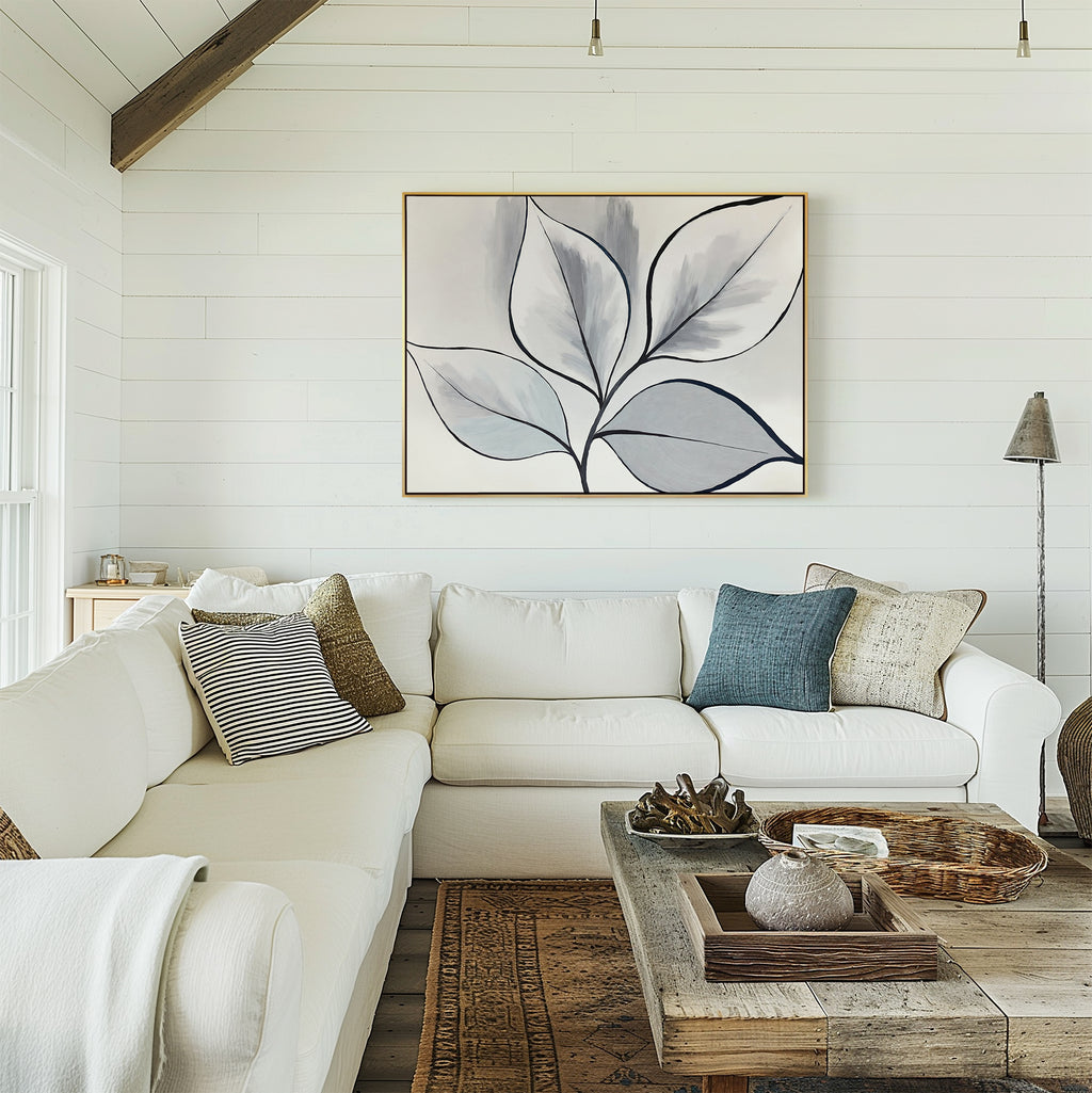 A cozy living room featuring a white sectional sofa, assorted throw pillows, a rustic wooden coffee table with decor, and the Silver Leaves Canvas Art - Horizontal displayed on a white shiplap wall. Warm, inviting, and full of modern style.