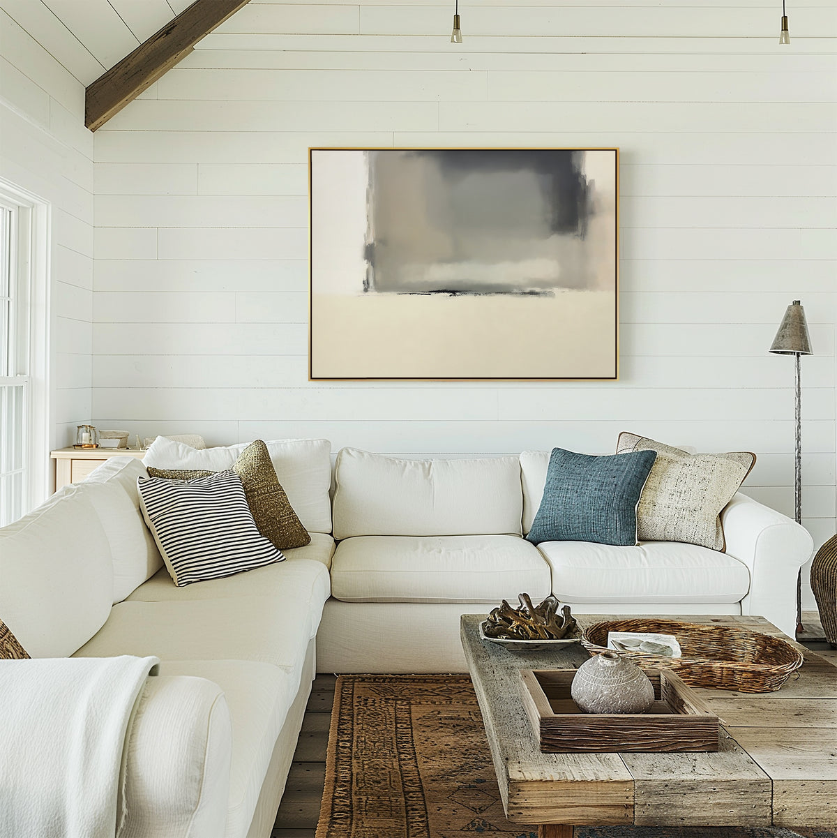 A cozy living room features a white sectional sofa, assorted throw pillows, a wooden coffee table, and the Smoke Boundary Canvas Art - Horizontal on a white shiplap wall. Natural light streams in from the window to the left.