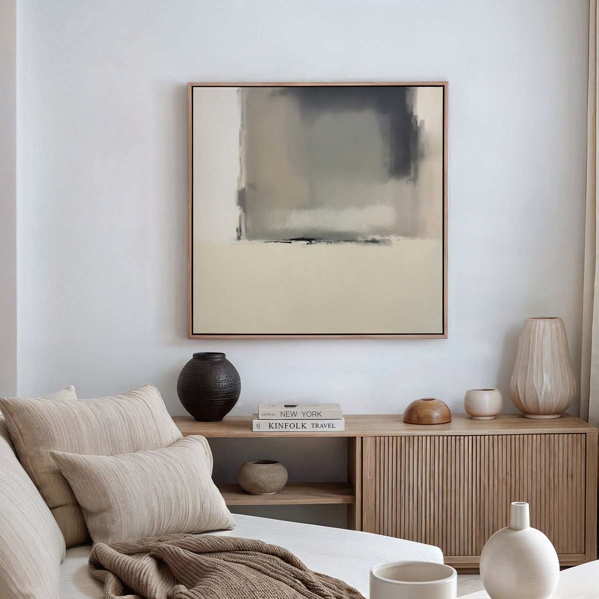 A modern, neutral-toned living room featuring a beige sofa with cushions, a wooden sideboard with vases and books, and the Smoke Boundary Canvas Art - Square in muted colors hanging on the white wall.