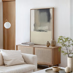 A modern living room with a light wood sideboard, the minimalist Smoke Boundary Canvas Art - Vertical adding neutral elegance, decorative vases, stacked books, a potted plant, a white globe floor lamp, and a white sofa with cushion for serene style.
