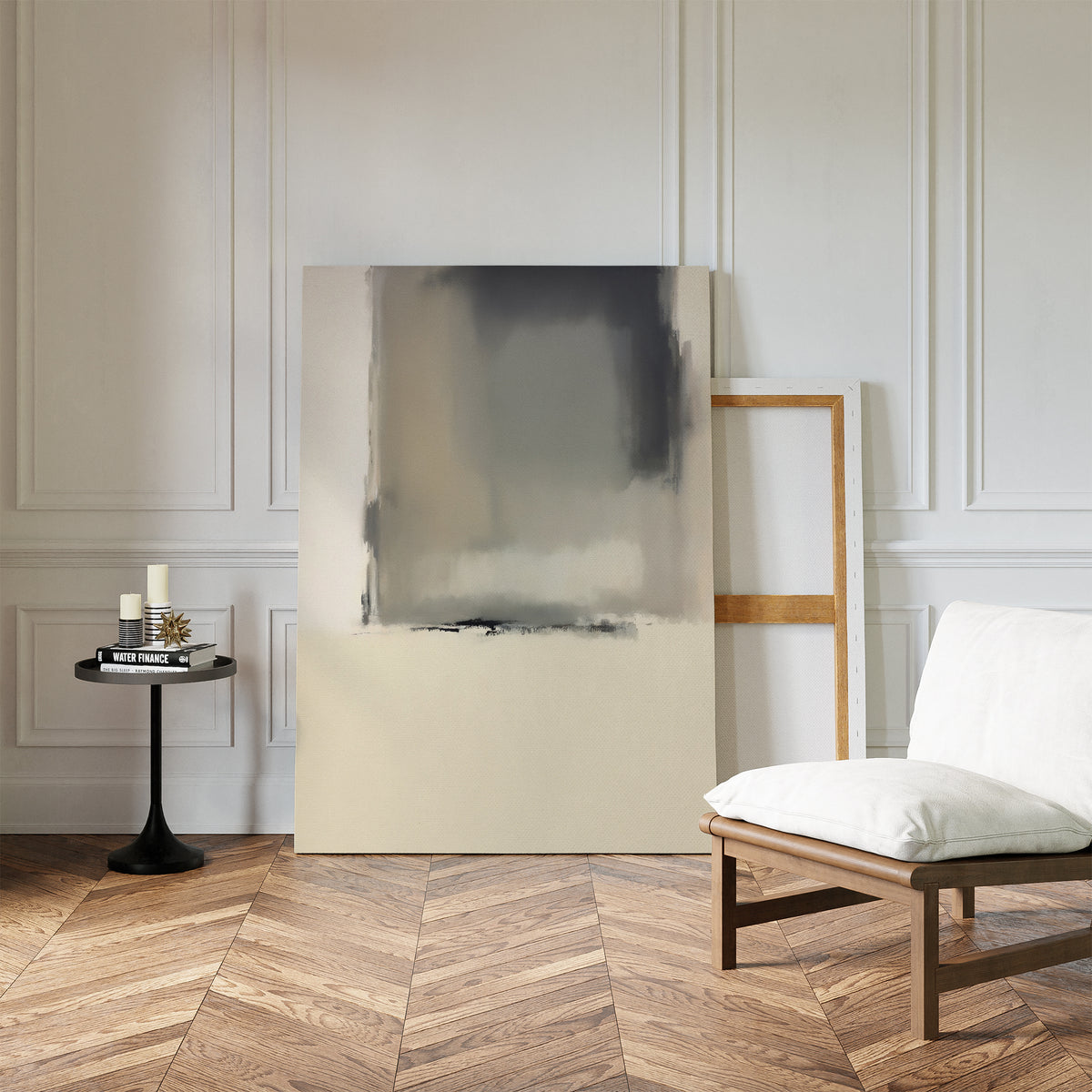 A minimalist room with herringbone wood floors, white paneled walls, a modern chair with white cushion, two large Smoke Boundary Canvas Art - Vertical prints leaning against the wall, and a small round black table with candles and a book.