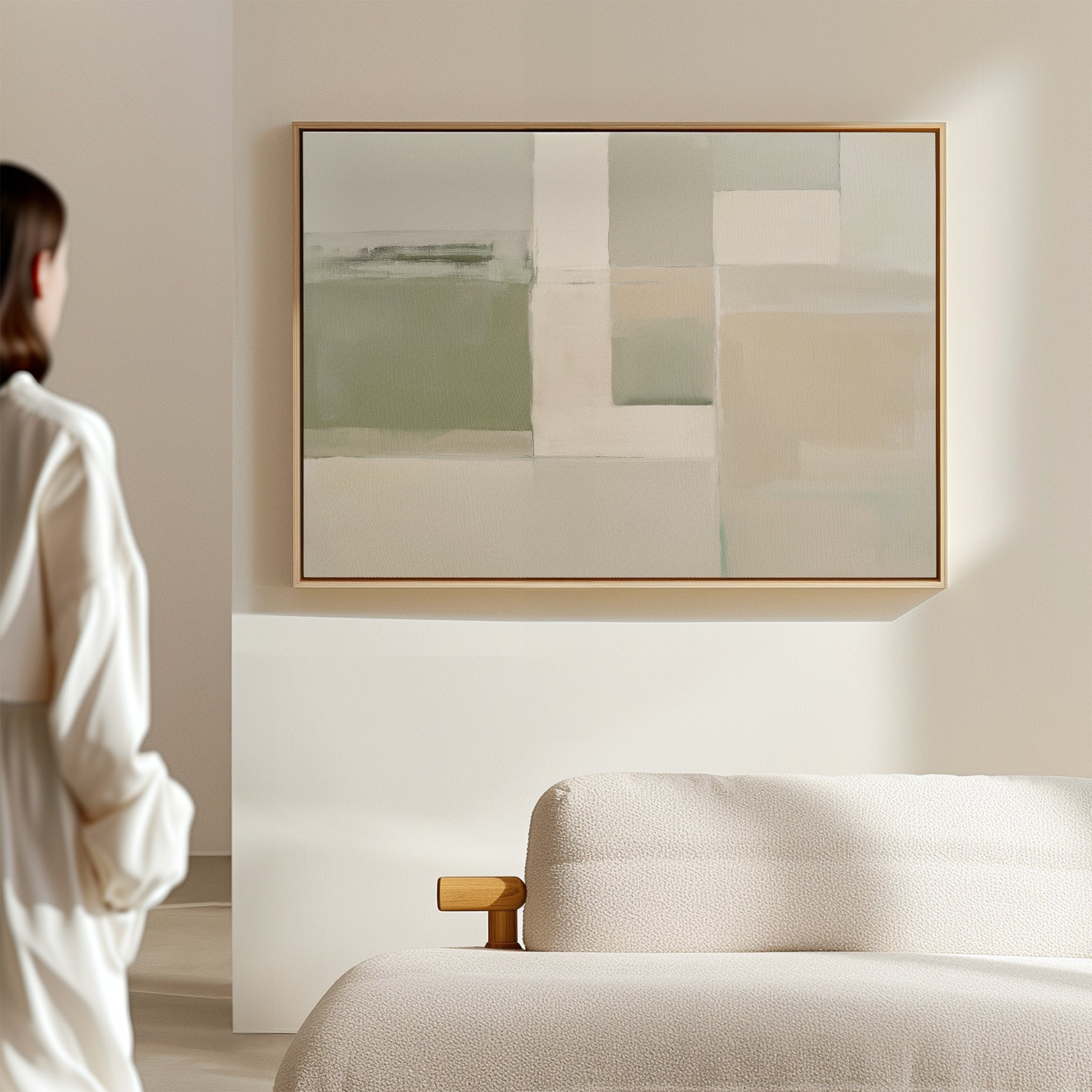 A person stands in a minimal, sunlit room with a light-colored sofa. The "Soft Geometric Planes Canvas Art - Horizontal" in muted tones adds a modern touch to the living room decor.