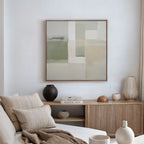 A minimalist living room featuring a beige sofa, cushions, a wooden sideboard with ceramics and books, and the Soft Geometric Planes Canvas Art - Square in soft neutral tones enhancing the contemporary feel on a white wall.
