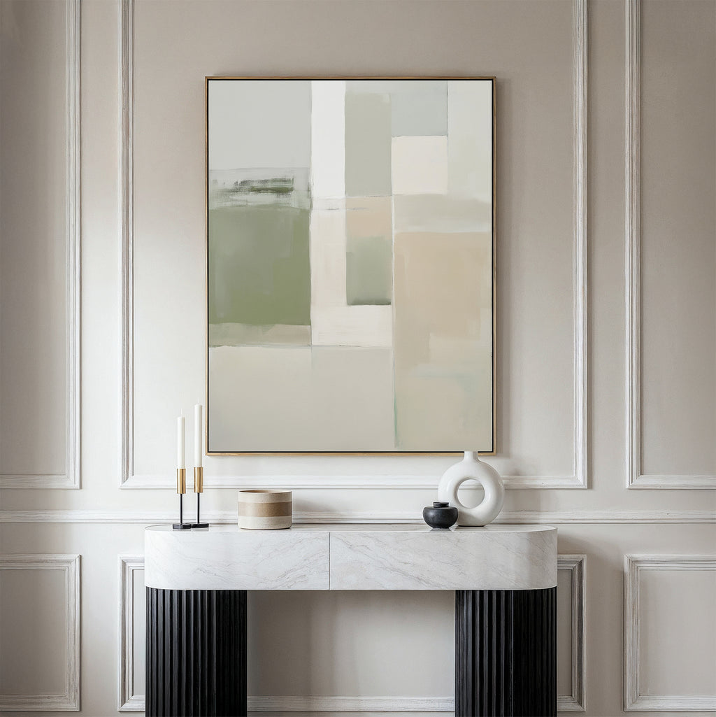 A minimalist console table with decorative objects stands against an elegantly paneled wall, topped by the Soft Geometric Planes Canvas Art - Vertical in neutral beige, green, and white tones for a contemporary look.