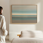 A person in white stands in a minimalist room, admiring the Soft Tide Layers Canvas Art—horizontal abstract layers of blue, teal, and beige above a light sofa—adding a tranquil Nordic Park vibe.