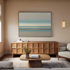 A modern living room features the Soft Tide Layers Canvas Art - Horizontal above a wooden sideboard, with a light wood coffee table, beige sofas, wall sconce, small vase of flowers on a soft rug, and natural light streaming in from the left.