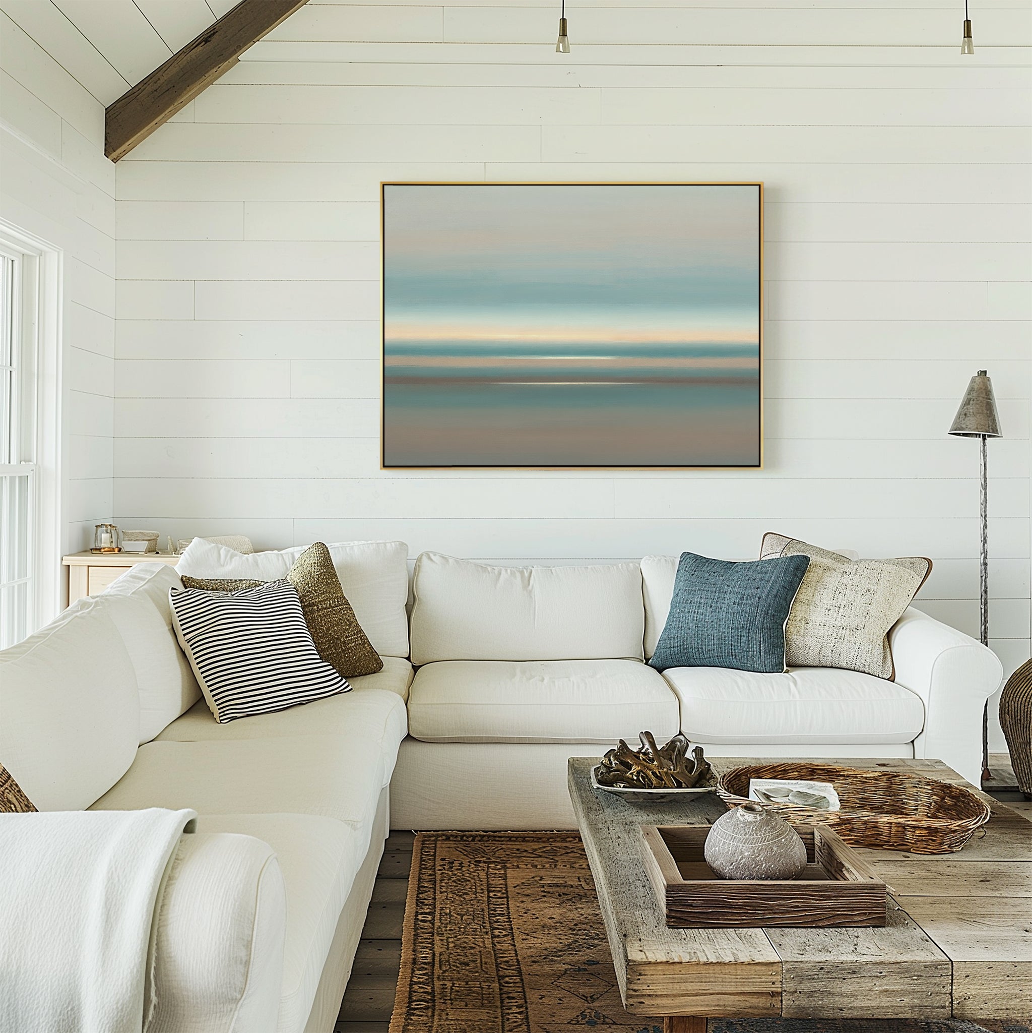 Bright living room with white shiplap walls, a large sectional sofa and assorted pillows, rustic wood coffee table with decor, and the Soft Tide Layers Canvas Art - Horizontal above the couch. Sunlight streams through the window.