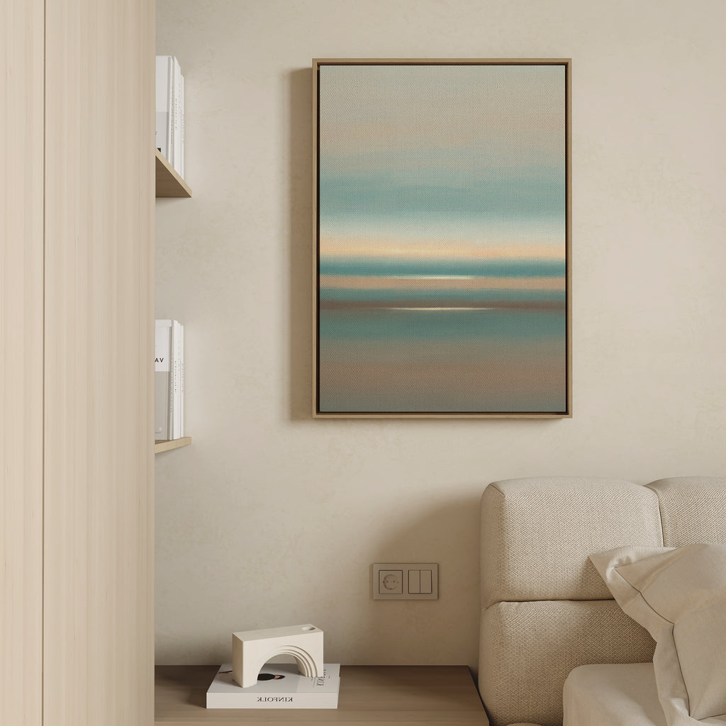 A modern living room features a light beige sofa, built-in wooden shelf with books and a small decor object, and the Soft Tide Layers Canvas Art - Vertical as calming coastal wall art in blue, teal, and beige on a cream wall.