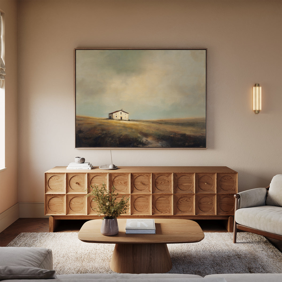 A cozy living room featuring a modern wooden coffee table, textured sideboard, neutral sofas, and the Solitary House Canvas Art - Horizontal above the sideboard. Warm lighting and soft tones enhance the inviting, rustic charm.