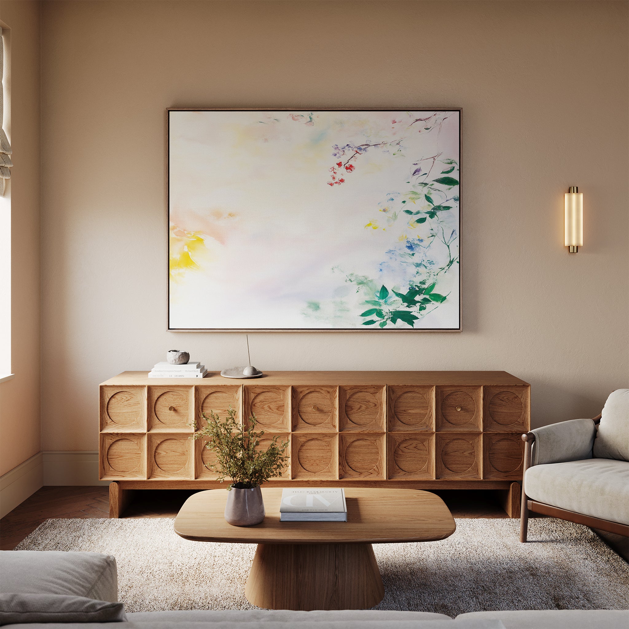 A cozy living room with a light sofa, wooden coffee table, textured sideboard, and the Spring Reverie Canvas Art - Horizontal featuring abstract florals above. A wall sconce and a vase with flowers complete the inviting decor.