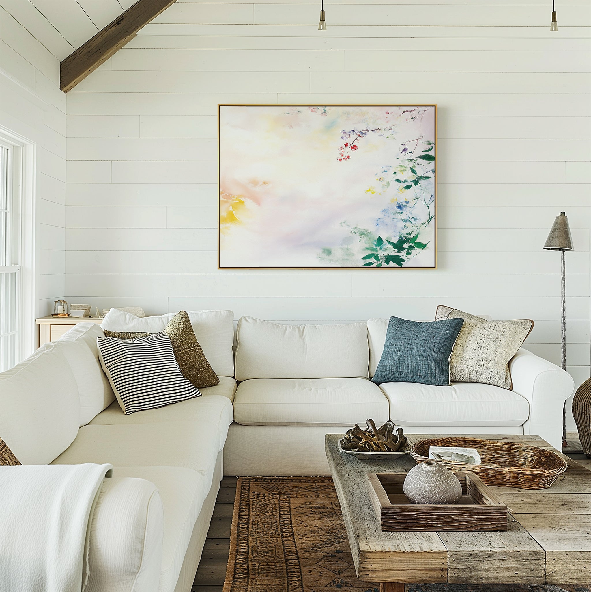 A cozy living room with a white sectional sofa, assorted pillows, a rustic wooden coffee table, woven accents, and soft floral decor highlighted by the Spring Reverie Canvas Art - Horizontal on white shiplap walls.