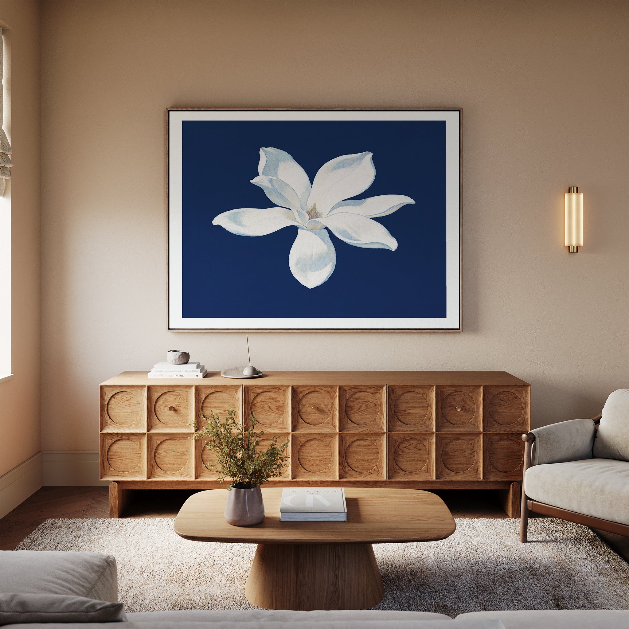 A modern living room featuring neutral walls, a light wood sideboard, beige sofa, wooden coffee table, and the Starlit Magnolia Canvas Art - Horizontal as contemporary wall art above the sideboard.
