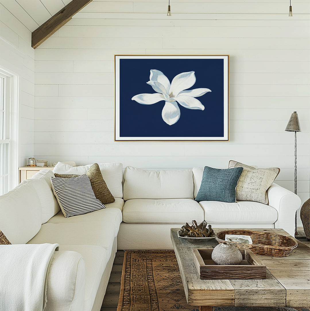 A cozy living room with a white sectional sofa, assorted pillows, a rustic wooden coffee table, and the Starlit Magnolia Canvas Art - Horizontal as contemporary wall decor on a deep blue shiplap wall.