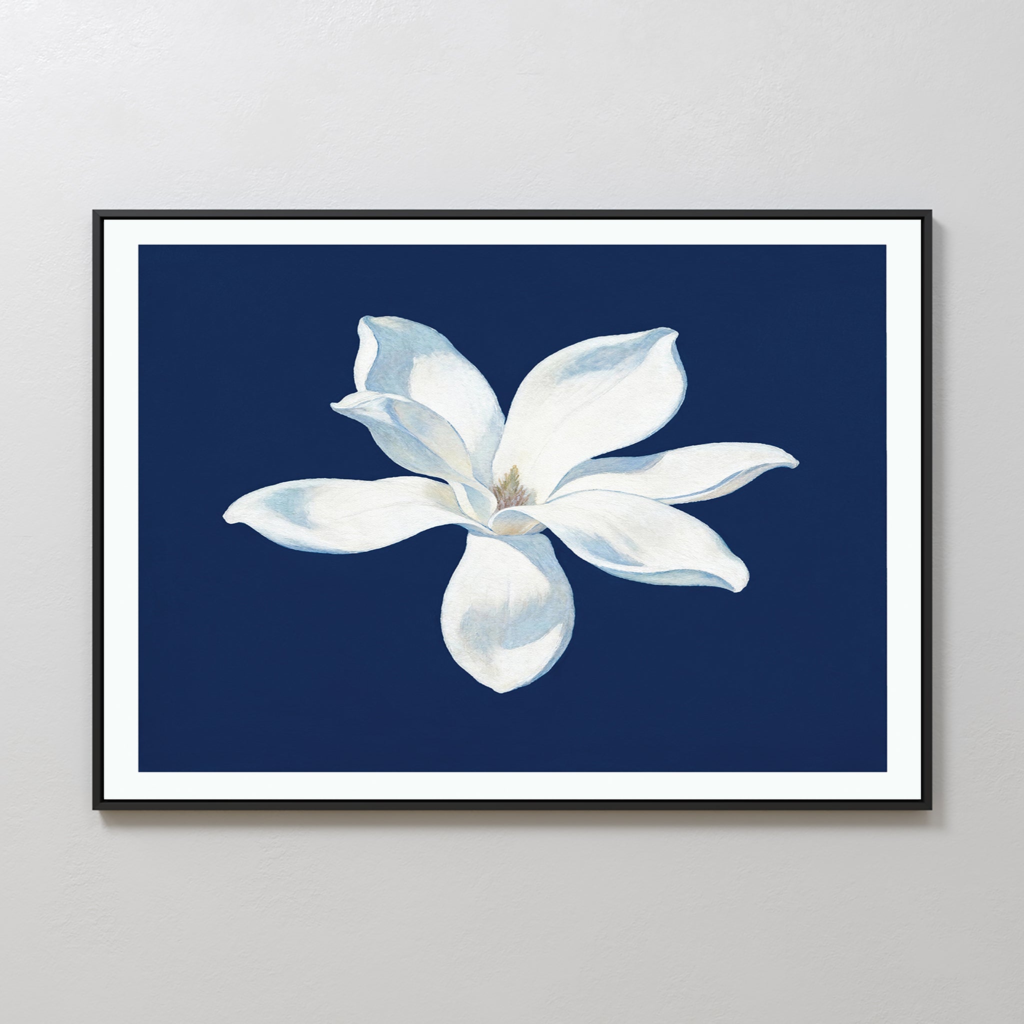 The Starlit Magnolia Canvas Art - Horizontal features a single white magnolia with soft shading on a dark blue background, creating striking contemporary wall art perfect for any light-colored room.