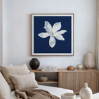 A modern living room features a beige sofa, striped pillows, and a light wood sideboard topped with vases and books. Above hangs the Starlit Magnolia Canvas Art - Square, completing the contemporary wall art aesthetic.