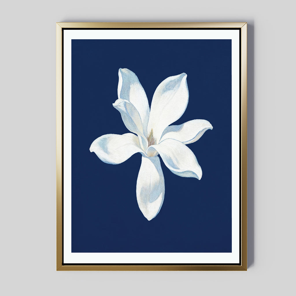 The Starlit Magnolia Canvas Art - Vertical features a single white magnolia flower with subtle shading on a deep blue background, framed in gold—modern wall art ideal for contemporary spaces.
