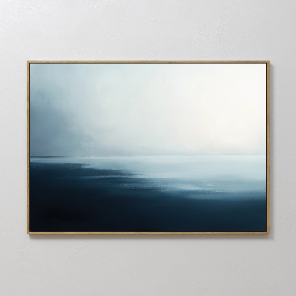 The Steel Harbor Mist Canvas Art - Horizontal features a minimalist painting of a calm sea beneath a cloudy sky in soft blue and white tones, framed in thin gold and ideal for display on a plain white wall.