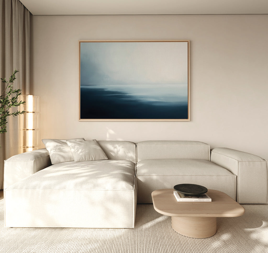 A modern living room with a light beige sectional sofa, low wooden coffee table, tall plant, and the Steel Harbor Mist Canvas Art - Horizontal above the sofa. Natural light from the left creates a serene Nordic Park ambiance.