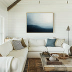 A bright, cozy living room with white shiplap walls, a large L-shaped sofa with assorted pillows, a rustic wooden coffee table, and the Steel Harbor Mist Canvas Art - Horizontal hanging above the couch.