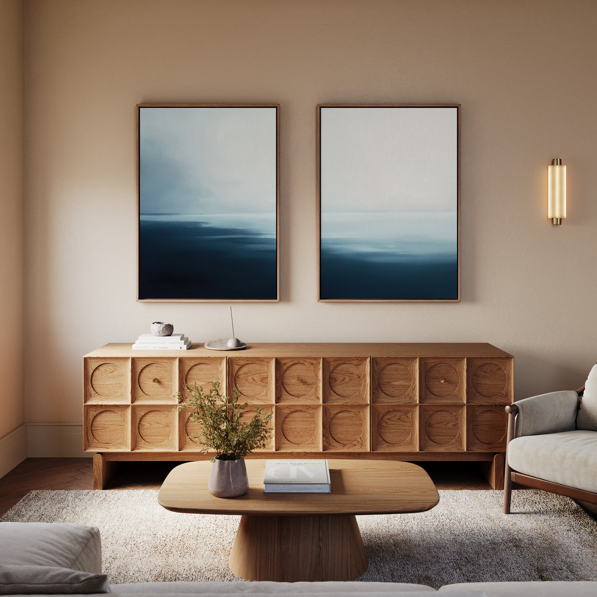 A modern living room features Steel Harbor Mist - Set Of 2 sideboards with geometric patterns, a matching coffee table, gray sofa, calming abstract blue wall art, a wall-mounted light fixture, and greenery for a stylish Nordic Park vibe.