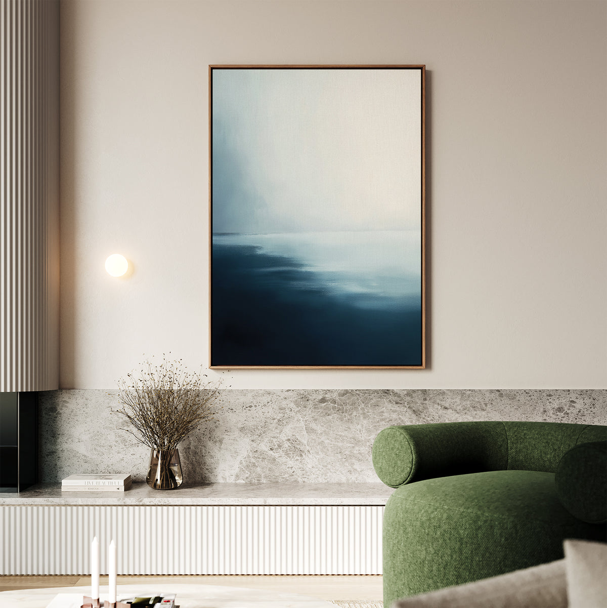 A modern living room with a green curved sofa, Steel Harbor Mist Canvas Art - Vertical featuring abstract blue and white hues, a marble ledge with dried flowers in a glass vase, and a round wall light.
